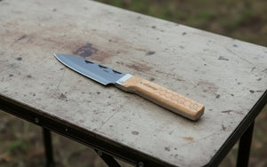 A folding chef knife with a blue steel blade and a beech wood handle, displayed in three different positions showing the blade extended, the blade folded, and the handle details.